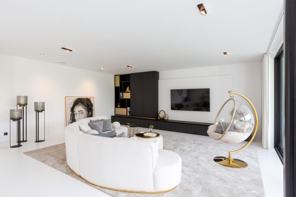 Woonkamer met witte PU Comfort+ gietvloer, donker maatwerkmeubel van Thonon en verfijnde gouden accenten