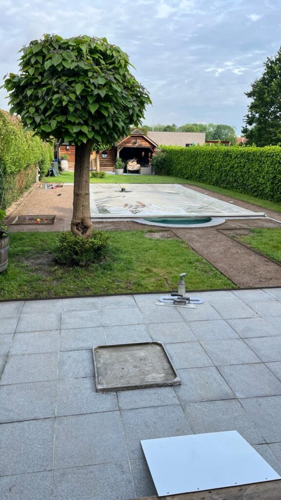 Verouderd terras en tuinpad zonder waterdoorlatende verharding, met zicht op zwembad