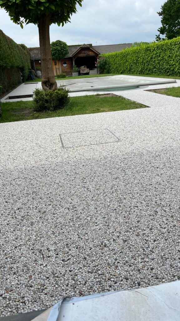 Terras en tuinpad met waterdoorlatende naadloze verharding tussen terras en zwembad