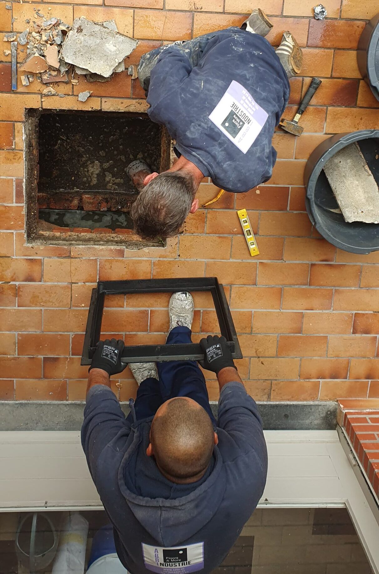 arbeiders herstellingen Arbeiders van Floors & More voeren herstellingen uit en werken het afvoerputje zorgvuldig bij tijdens de terrasrenovatie