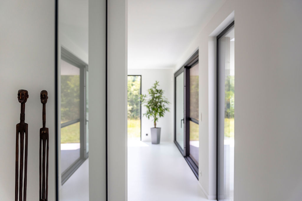 Woonkamer met naadloze witte gietvloer als perfecte basis, gecombineerd met een strakke witte maatkeuken en veel natuurlijke lichtinval.