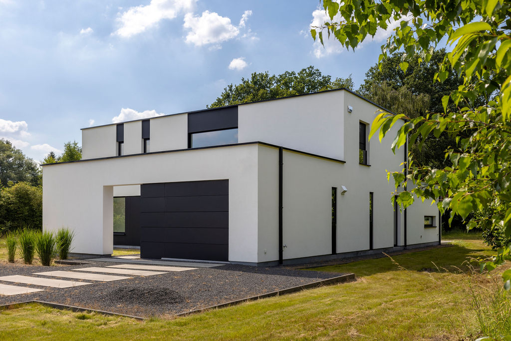 Moderne vrijstaande villa in Boormeerbeek met witte gevel, zwarte accenten en grote raampartijen, ontworpen door Sens Architecten.