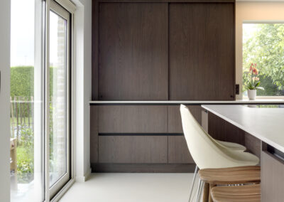 Lichtbeige Mineral Touch gietvloer in een stijlvolle nieuwbouwwoning met een donkerbruine maatkeuken, geplaatst door Floors & More.