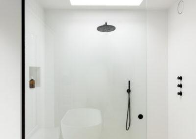 Grote inloopdouche met lichtkoepel, wanden in Mineral Touch afwerking en zwart kraanwerk met glazen douchewand in Lennik