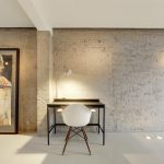 Werkhoek met bureau en designstoel op Mineral Touch gietvloer tegen bakstenen muur.