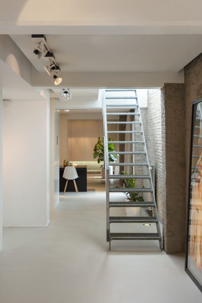 Gang met Mineral Touch gietvloer en stalen trap in gerenoveerde loftwoning.