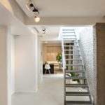 Stalen trap en bakstenen muur boven Mineral Touch gietvloer in modern interieur.