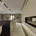 Lange zwarte tafel met stoelen op Mineral Touch gietvloer in open keuken.