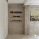 Mineral Touch gietvloer tegen bakstenen muur met wandplanken in loftinterieur.