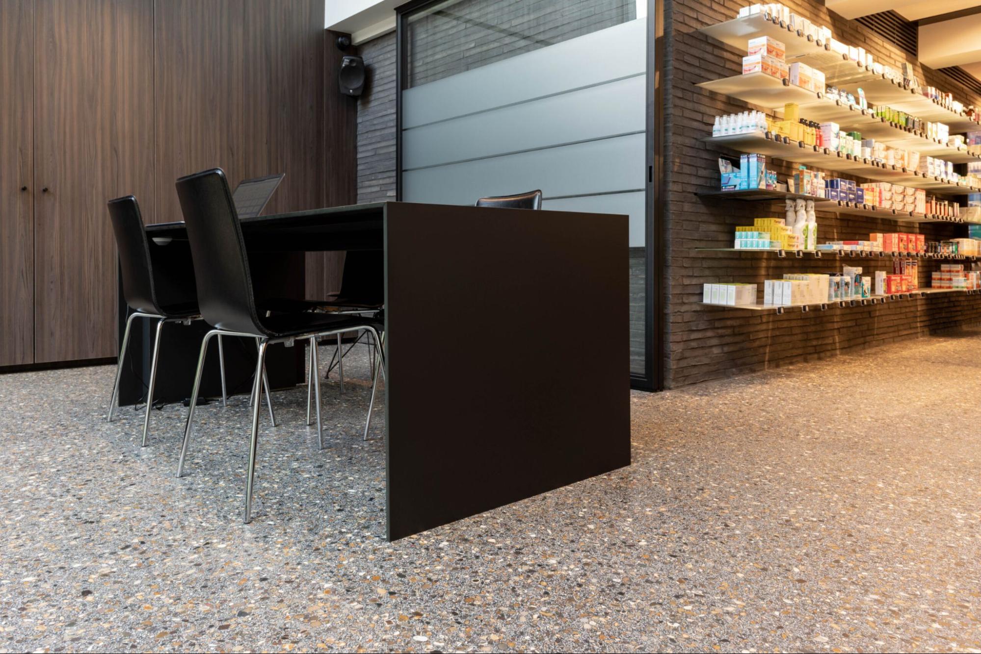 Moderne apotheek met balie en duurzame terrazzo vloer met natuurlijke steenkorrel.