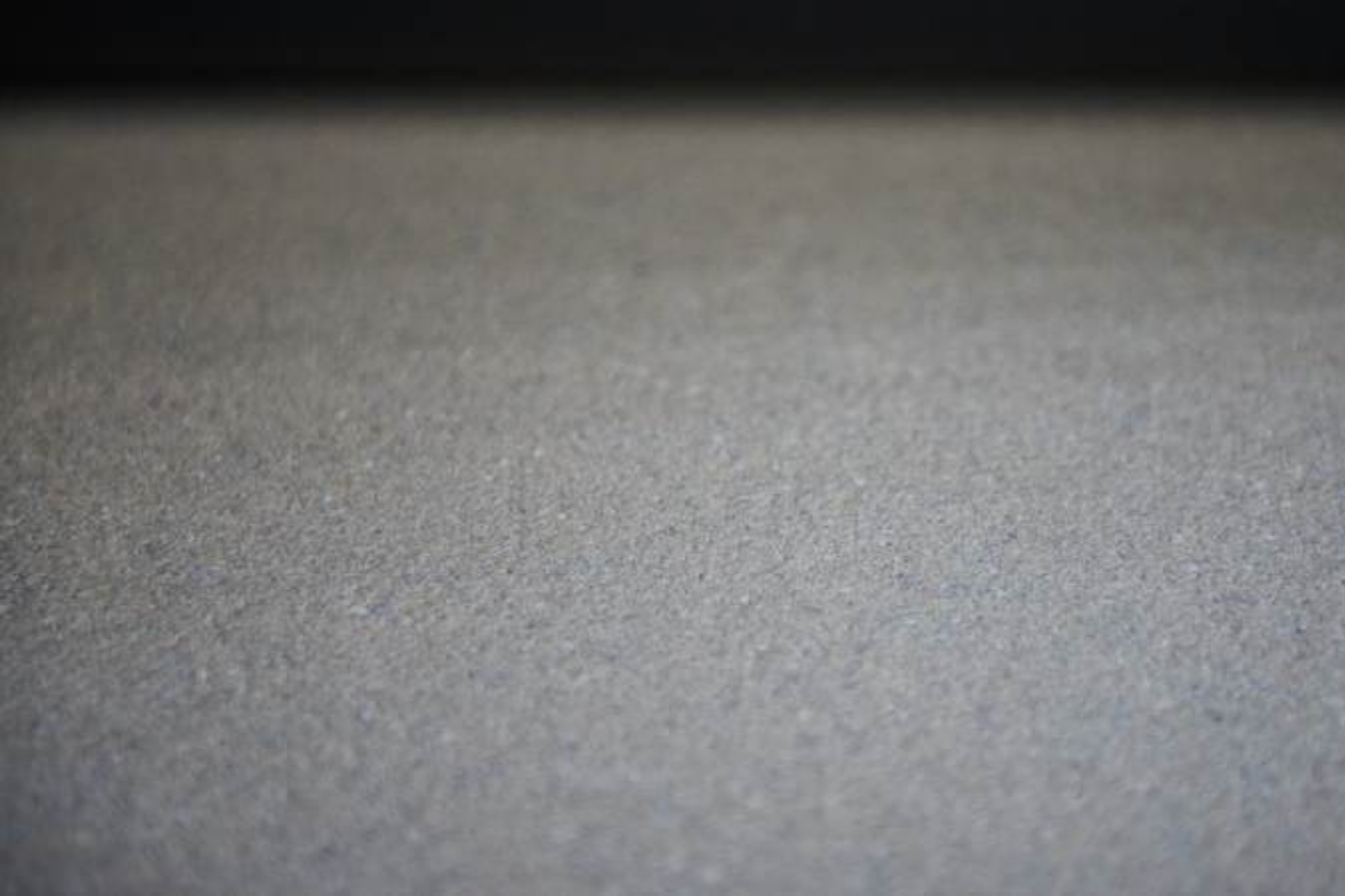 Close-up van een donkere troffelvloer die de fijne korrel en gesloten structuur toont