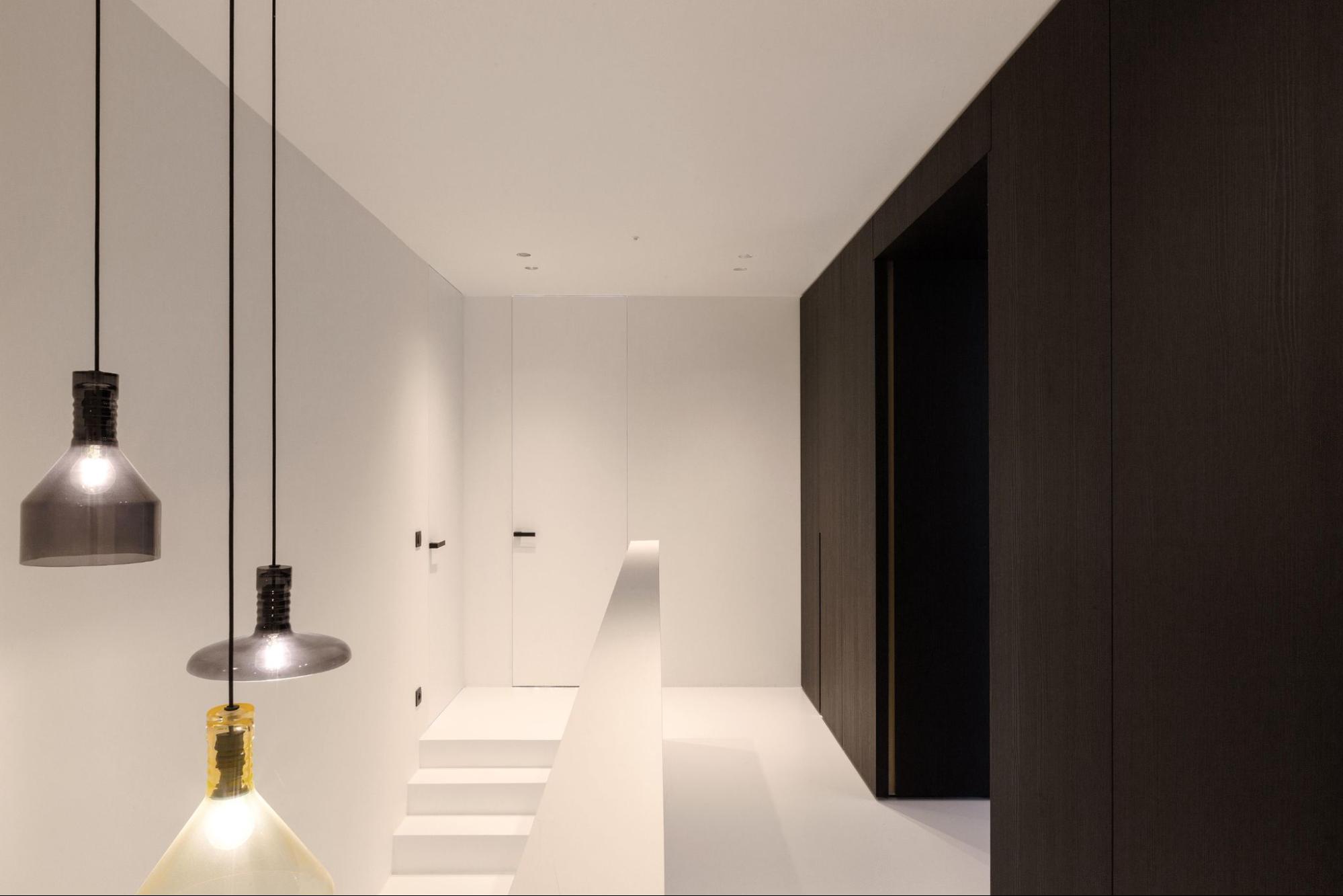 Minimalistische hal en trap met doorlopende gietvloer voor een strak interieur