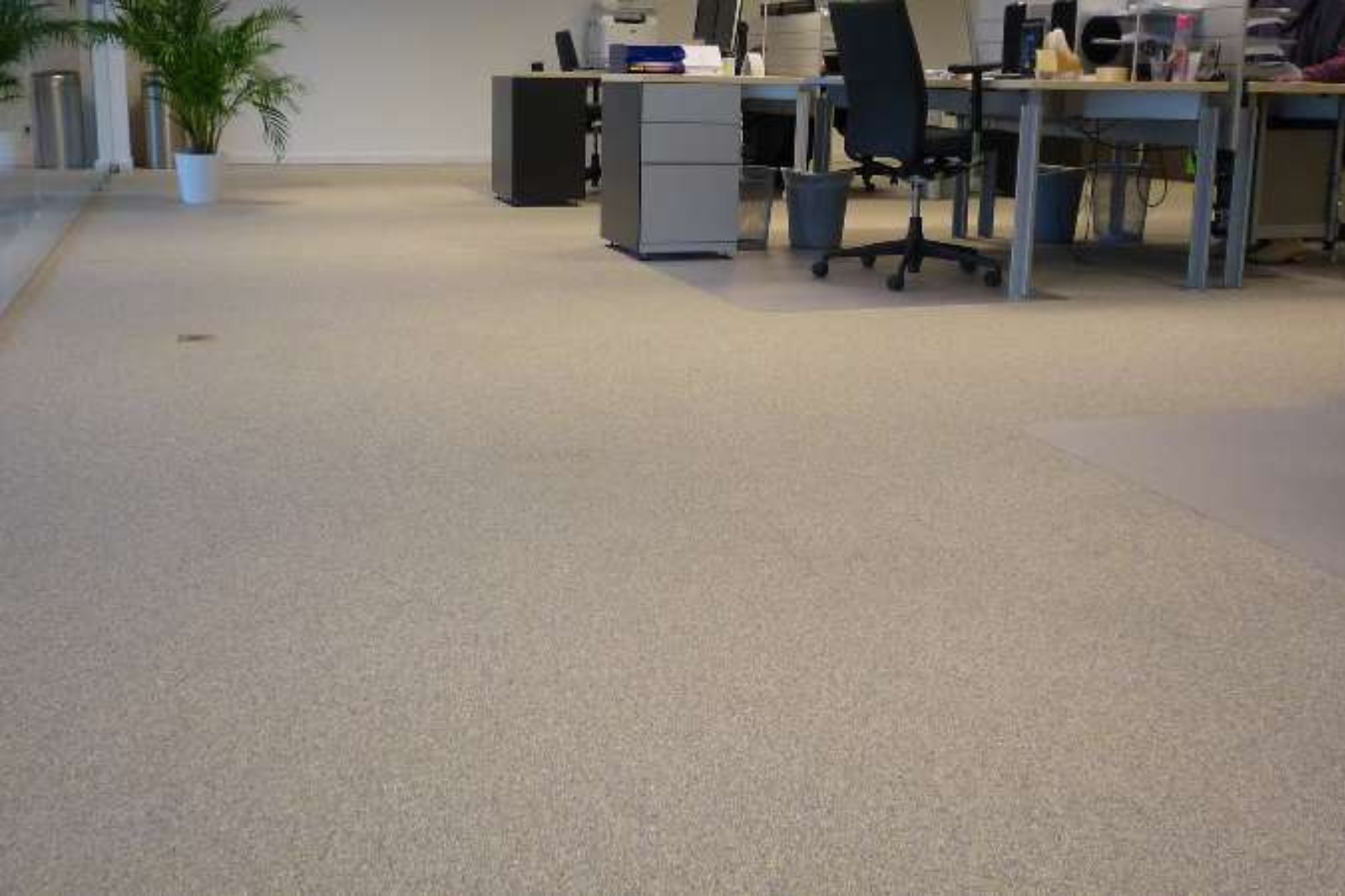 Modern kantoorinterieur met naadloze marmertapijt vloer en bureaus in open werkruimte.