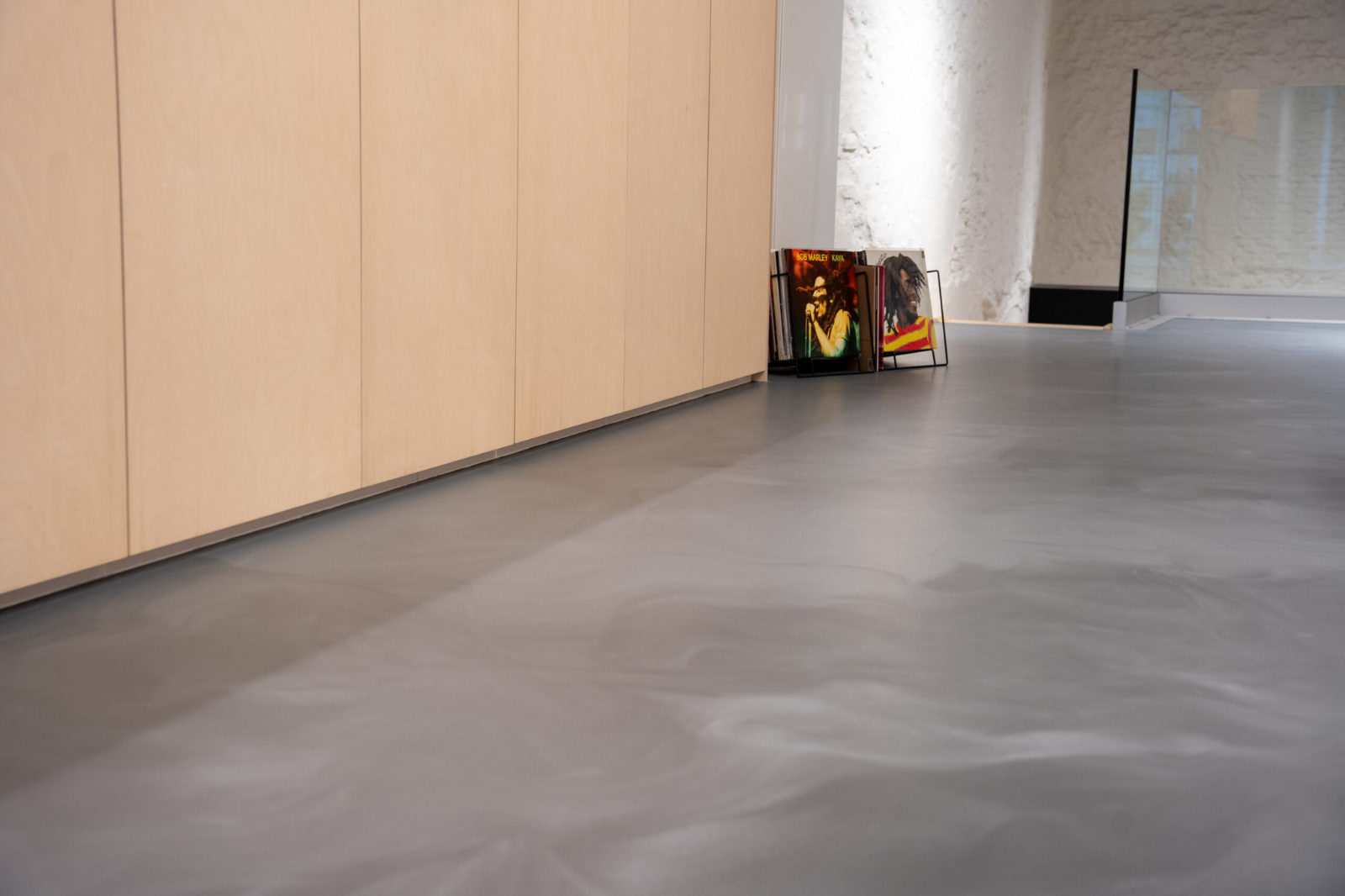 Close-up van een grijze PU gietvloer bij een renovatie met houten kasten en moderne afwerking<br />
