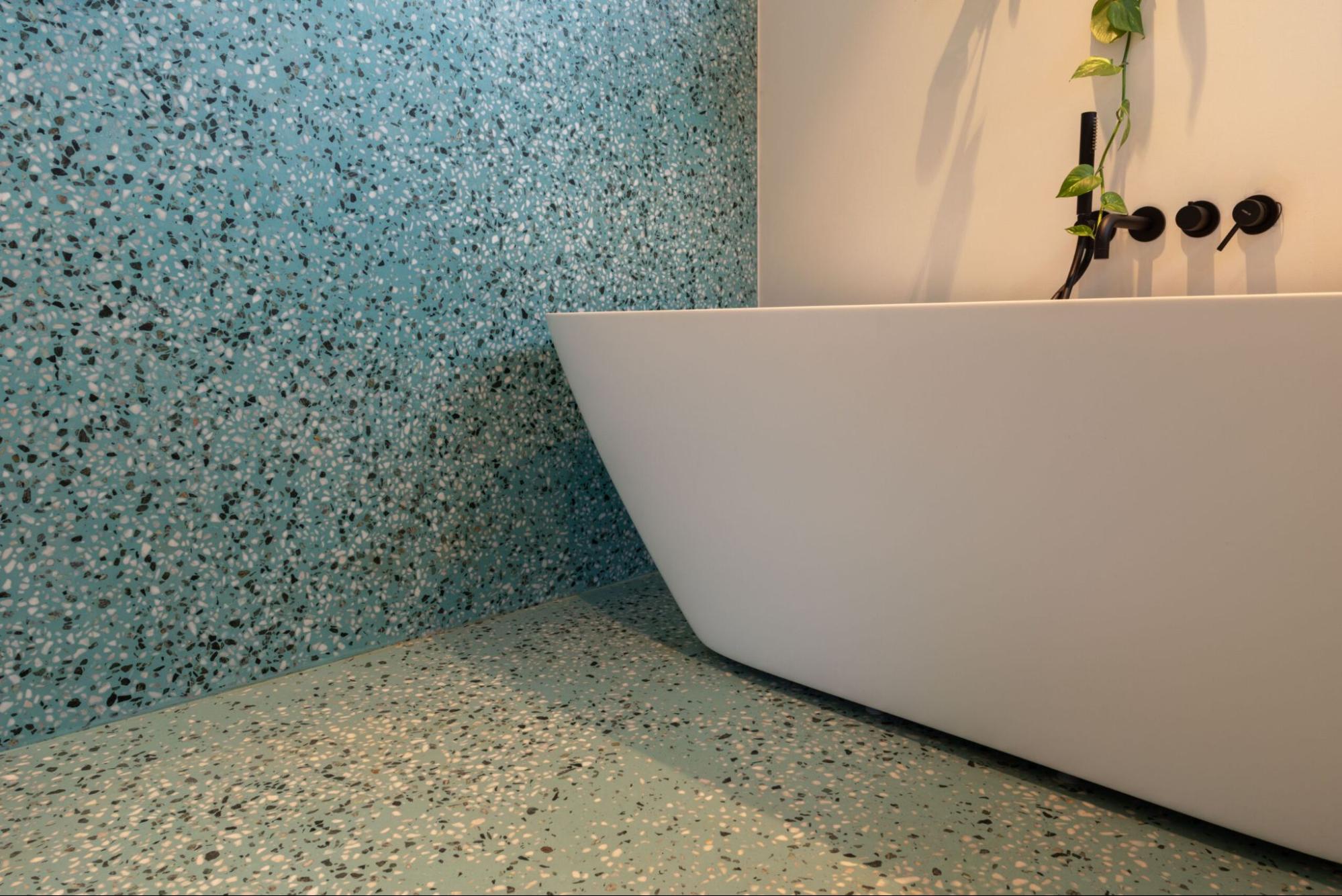 Moderne badkamer met vrijstaand bad en turquoise terrazzo vloer en wandafwerking.<br />
