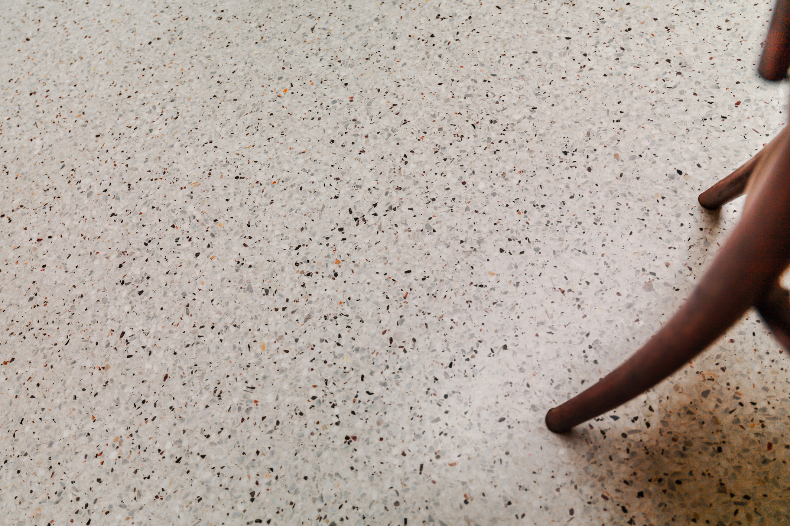 Close-up van een terrazzo gietvloer met fijne marmerkorrels en naadloze afwerking in een modern interieur.